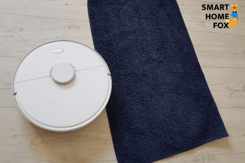 Saugroboter bei der Reinigung eines schwarzen Teppichs.